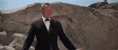 Movie gif. Harvey Korman as Hedley Lamarr in Blazing Saddles stands in a suit in front of a large rock formation, raising his arms slowly and theatrically like a stage performer while saying "now go do that voodoo that you do so well!!!" which appears as text.