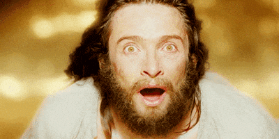 Movie gif. Hugh Jackman as Tomas looks up at the sky with dazzled eyes and an open mouth like he has just seen something incredible. Golden light washes over him and his hair flows behind him in the wind. 