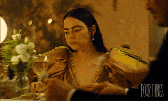 Movie gif. Emma Stone as Bella in Poor Things. She's sitting at a table in a big yellow gown and she's disgusted by the food she's chewing. She unhesitatingly spits out her food back onto her plate.
