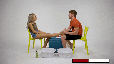 a man is giving a woman a foot massage while sitting at a table .