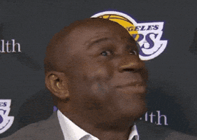 Celebrity gif. Magic Johnson with a tight smile and bright eyes, shaking his head no