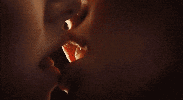 Video gif. A zoomed-in shot of two people french kissing.