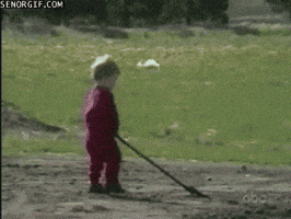 Video gif. A young child in a patch of dirt lifts their shovel, and loses control, accidentally throwing dirt back on themself.