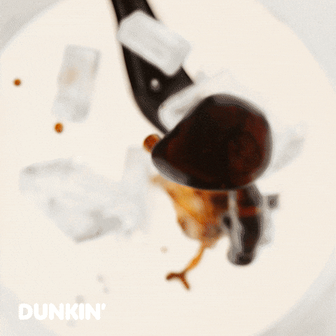 Sponsored gif. Ice and Dunkin’ Donuts coffee come flying toward the camera. Text reads, “Morning fuel.”