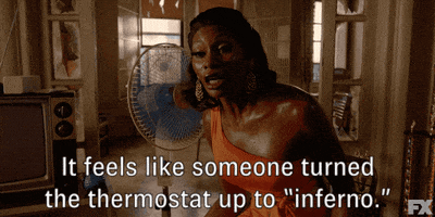 TV gif. Dominique Jackson as Elektra in Pose sweats as she stands in front of a fan and speaks emphatically, saying, "It feels like someone turned the thermostat up to inferno."