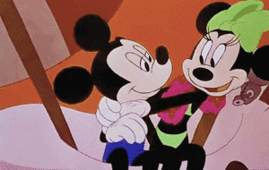 Disney gif. Minnie Mouse plants a big smooch on a surprised Mickey Mouse with her arms wrapped tight around him.