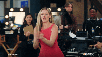 TV gif. Taylor Louderman as Tami on Kenan steps forward among crew workers on a set clapping her hands and cheering loudly.