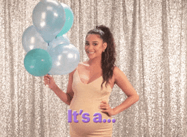 Celebrity gif. Shay Mitchell holds gray and blue balloons in one hand and then rubs her hands over her pregnant belly as she says, “It’s a…boy!”