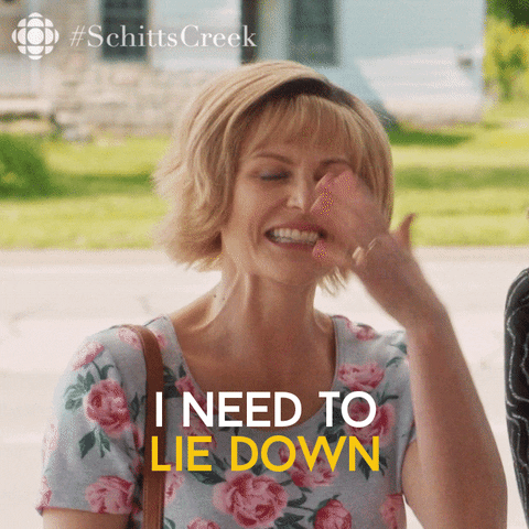 TV gif. Jenn Robertson as Jocelyn Schitt in Schitts Creek fans herself and smiles through her discomfort. Text, "I need to lie down."