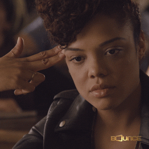 Movie gif. Tessa Thompson as Samantha in "Dear White People" appears blank and bored, sitting at a desk with her fingers to her temple in the shape of a gun.