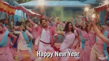 Movie gif. A huge Bollywood dance scene from the movie Mauli. Characters dance in the streets amid clouds of color pigment powder to celebrate the new year. Text. "Happy New Year!"