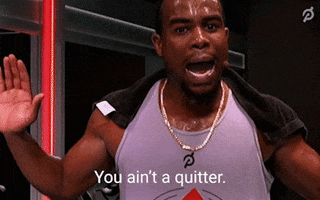Celebrity gif. Alex Toussaint of Peloton places a towel over his sweaty shoulders as he looks intently ahead with perseverance. Text, "You ain't a quitter."