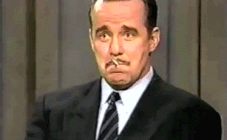 Celebrity gif. Phil Hartman is holding a cigarette between his teeth which he spits out as he gives a big reaction to something he sees. His eyes go wide and he says, "Wow!"