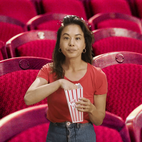 TV gif. Jen Rubinz as Jen from "Legal Dads" edited to be standing in front of an empty theater, eyes wide and fixed on a single point, repeatedly shoving small handfuls of popcorn into her mouth.