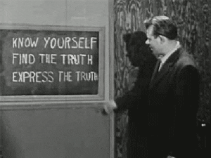Man pointing to board that says "Know yourself, find the truth, express the truth."