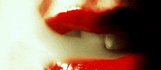 Video gif. Pair of glossy red lips seductively inhales wisps of smoke.