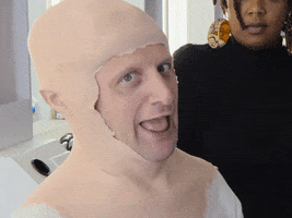 Celebrity gif. Tim Robinson from I Think You Should Leave with Tim Robinson wears a rubber head prosthetic that is ill-fitted on his head. He sticks his tongue out and holds his hand up in the rock and roll symbol.