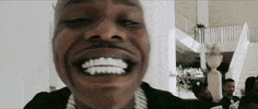 Celebrity gif. DaBaby fills the frame with his teeth as he leans towards us and grins with a wide smile and full teeth.