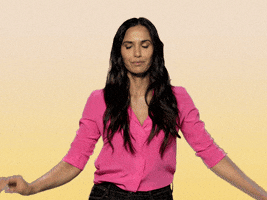 Celebrity gif. Padma Lakshmi is dancing and doing a very good hip roll as her hands are up in the air, feeling herself.