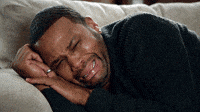TV gif. Anthony Anderson as Dre on Blackish weeps while lying sideways on a sofa with his hands tucked under his head.