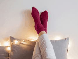 Feet with red socks resting on the wall with text that says "oh so cozy." GIF