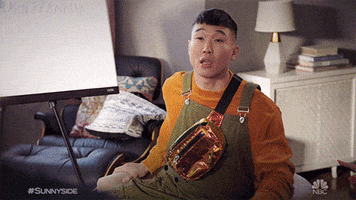 TV gif. Joel Kim Booster as Jun Ho in Sunnyside. He sits on a couch and gazes at the person proudly. He says, "Boom," while using one hand to mimic an explosion and confetti comes out of his hand.