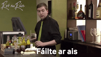 Video gif. Bartender moves towards someone with open arms and says, “Failte ar ais.”