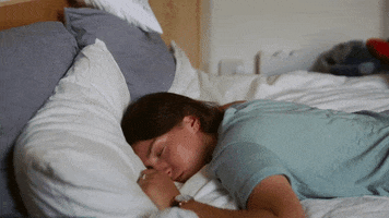 Video gif. Woman is sleeping facedown on her bed and she continues to sleep soundly as a sign pops up behind her that reads, "No."