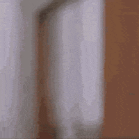 Video gif. A man chewing gives a big thumbs up in a doorway as if approving of the food. 