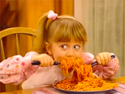 TV gif. Mary Kate or Ashley Olsen as Michelle Tanner from Full House starts devouring a huge plate of spaghetti using two utensils.
