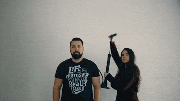 Video gif. A woman holds a bike pump that is connected to a man's head. She pumps it and the man's head gets larger and larger and he blinks his huges eyes at us.