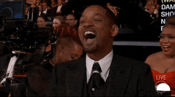 Celebrity gif. Will Smith is seated at the Oscars and laughs, mouth wide open. Other attendees in the background chuckle and shake their heads.