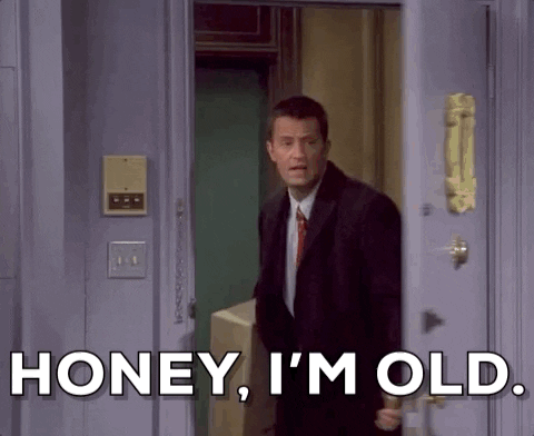 Vrienden gif. Matthew Perry terwijl Chandler de deur naar het appartement openzwaait en sarcastisch zegt: "Schat, ik ben oud." Hij draagt ​​een grote doos in zijn hand.