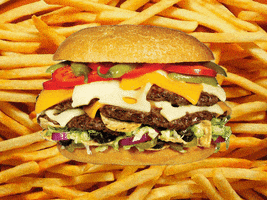 Photo gif. A triple cheeseburger with the works shakes back and forth in front of a background of cooked french fries.