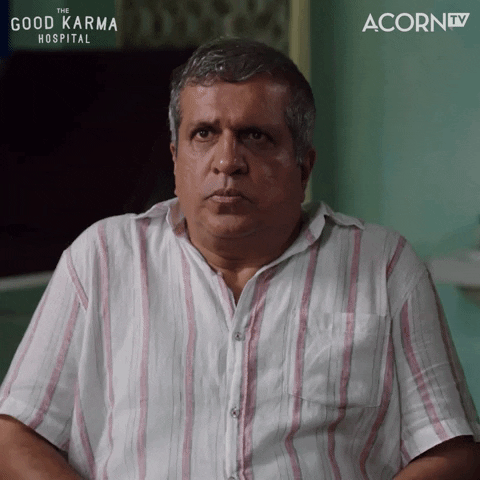 TV gif. Darshan Jariwala as Dr. Ram Nair in The Good Karma Hospital. He's sitting in a chair and he sits up slightly before looking shocked and spinning around to look at who walked in.
