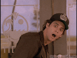 Movie gif. Jim Carrey in character, dressed in brown uniform, stands in front of a door, looks up and reels backward and makes a silly face, as if he just realized something obvious.