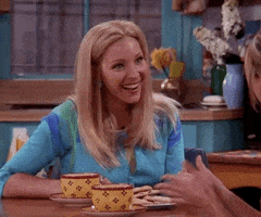 Friends gif. Lisa Kudrow as Phoebe sits up straight, enthusiastically smiling and nodding.
