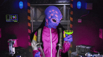 Video gif. An alien has made themselves a cocktail in its spaceship and it looks at the cocktail before looking at us shocked, saying, "Ay, que delicia!"
