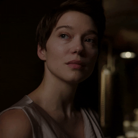 Movie gif. Lea Seydoux as Caprice in Crimes of the Future stares over her shoulder inquisitively. 