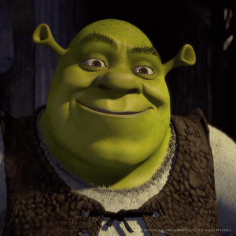 Movie gif. Shrek shrugs his shoulders in acquiescence and smiles contentedly.