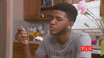 Reality TV gif. Man on 90 Day Fiance sits in the kitchen, looking at a spoonful of cake he’s holding up. He slightly shakes his head as he chews on food and says, “You’re just crazy.”
