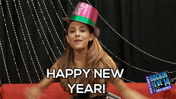 Celebrity gif. Ariana Grande sits on a couch at Dick Clarke’s New Year’s Rockin’ Eve 2014. She wears a pink Happy New Year top hat and throws her arms up in celebration as she says, "Happy New Year!”