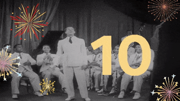 Video gif. In black and white, Cab Calloway announces something in front of his jazz band, then turns towards them and gestures for them to begin playing. In an overlay we see fireworks exploding and a countdown. Text, “10, 9, 8, 7, 6, 5, 4, 3, 2, 1, Happy New Year!”