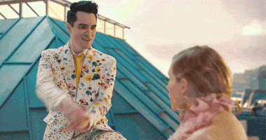 Music video gif. Brendon Urie is proposing to Taylor Swift in a music video. He has a crazed look on his face and she looks bored.