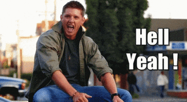 Video gif. Man rolls his shoulder excitedly, doing a little dance, sitting by the street. Text reads, "Hell Yeah!"