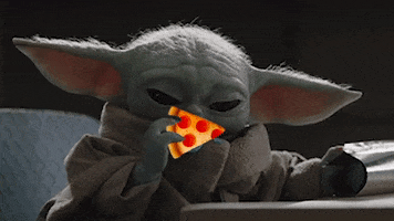 Disney gif. Baby Yoda sniffs a slice of pizza then looks up curiously.