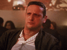 TV gif. Tim Robinson in I Think You Should Leave with Tim Robinson shields his eyes and perplexedly looks into the distance as the colors of police car lights flash upon his face. Text reads, "What the heck."