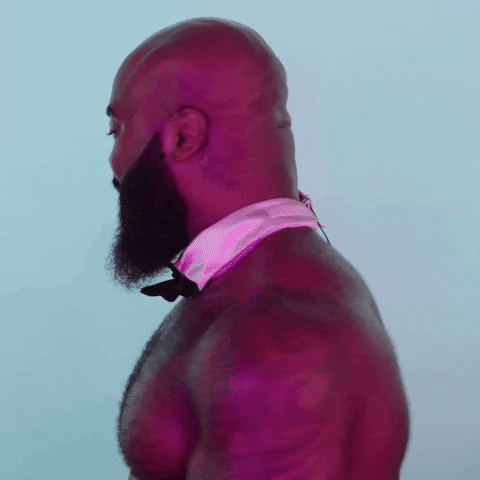 Video gif. A shirtless, muscly man with a bowtie collar turns to us, smiling wide. He gives two enthusiastic thumbs up and says, “good luck, baby!”