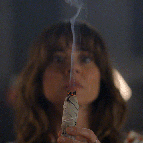 smudging stick made with sage being used to cleanse negative energies from a room gif