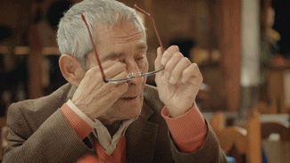 Movie gif. Actor Sergio Chamy as himself in The Mole Agent wipes his eyes with a tissue before replacing his glasses. 